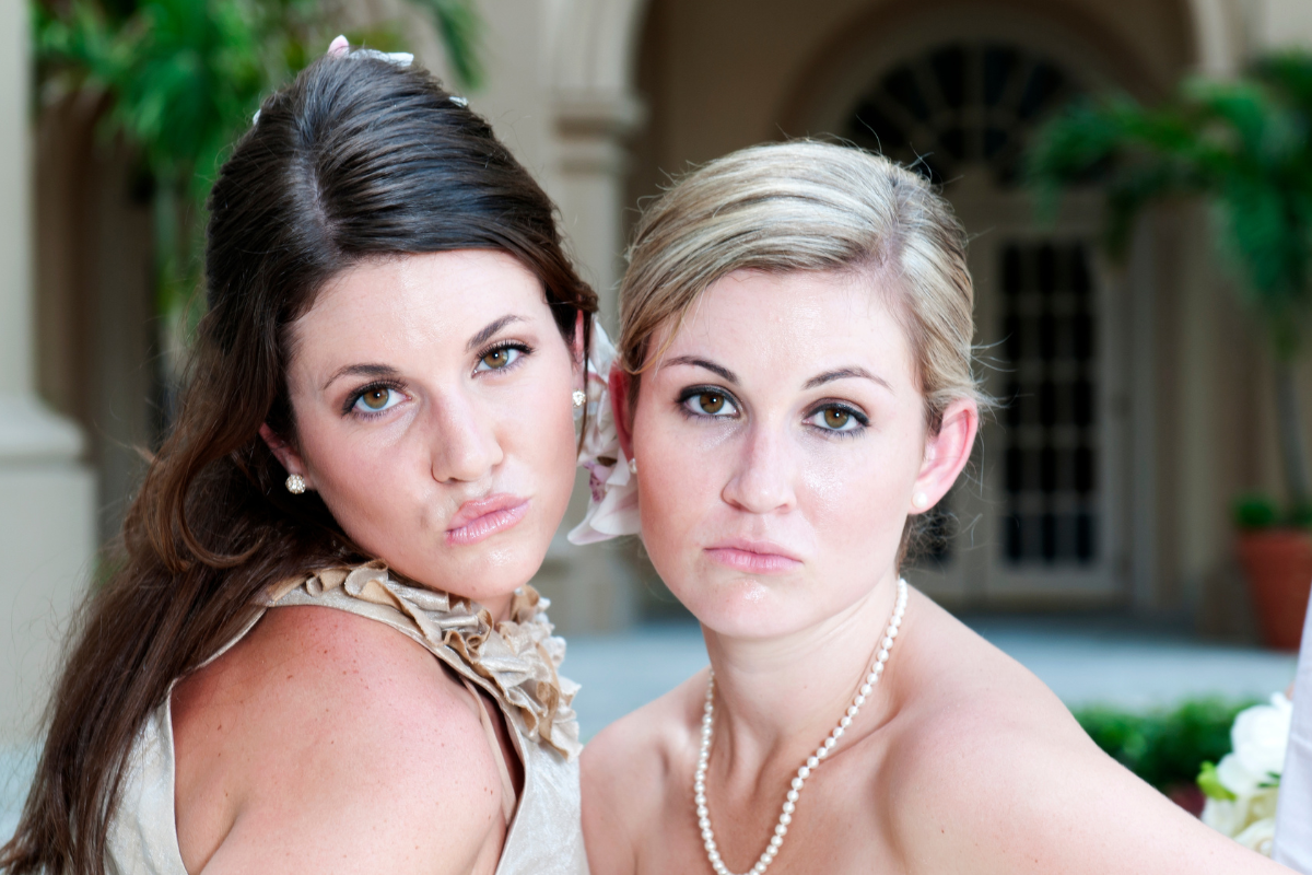 a bride sitting beside her friend matron of honor speech, looking at the camera blowing kisses.