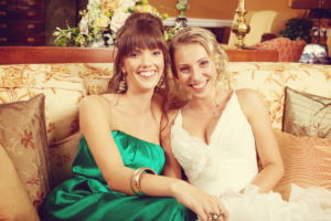 a bride sitting beside her sister and both smiling.