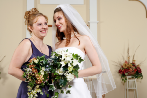 a bride standing and laughing beside her friend maid of honor.