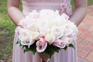 an image of a maid of honor holding a bucket of flowers in her hand.