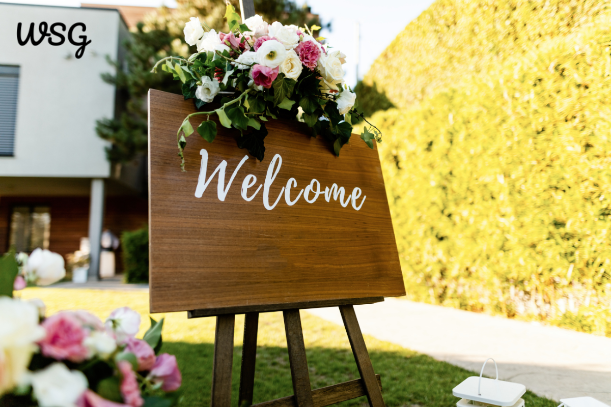 Wedding welcome speech sign with flowers on display at a wedding venue entrance.